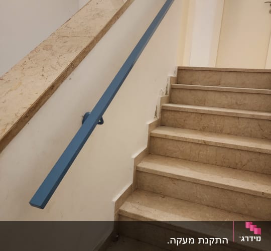 מעקה כחול מותקן על קיר מדרגות שיש